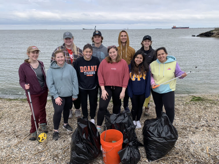 Doane students posing after cleaning up a beach